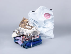 En hög med begagnade kläder och skor framför en Erikskasse.