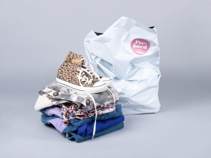 En hög med begagnade kläder och skor framför en Erikskasse.