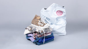 En hög med begagnade kläder och skor framför en Erikskasse.