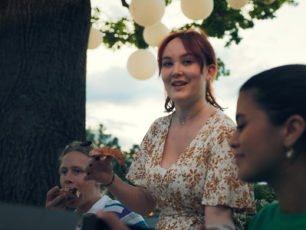 En ung person håller en pizza slice i handen.