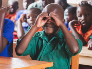 Pojke som håller sina händer framför ögonen som om han höll i en kikare.