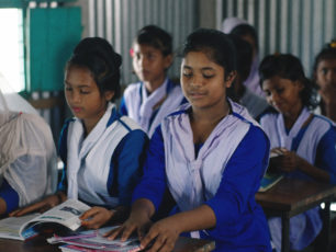 En skolklass med flickor sitter och läser i skolböcker.