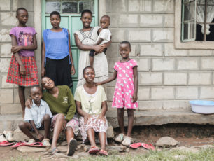 En bild på en grupp med åtta personer från Kenya som står uppradade framför en vägg. De är i blandade åldrar.