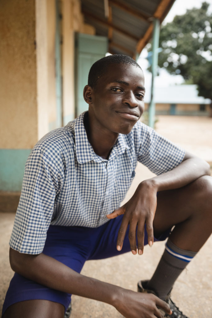 Pojke (Lawrence) sitter i avslappnad cool pose, på huk, och ser nöjd ut.