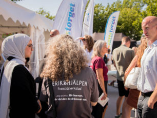 Ryggtavlor på två ungdomar som pratar med makthavare på Almedalen. En av ungdomarna har en Erikshjälpen Framtidsverkstad tshirt.