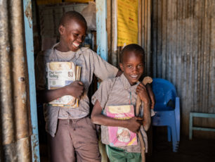 Två bröder står med skolböckerna redo i dörren. 