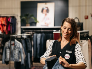 En glad volontär fixar till en skyltdocka i Erikshjälpen Second handbutik