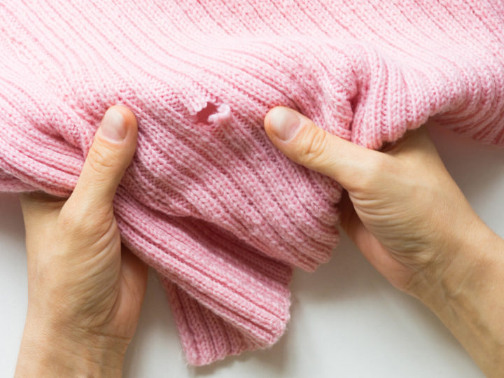 Ett par händer håller ett tyg med ett hål i.