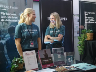 Ett par värvare från Erikshjälpen Ungagerad står vid monterbord på ett event.