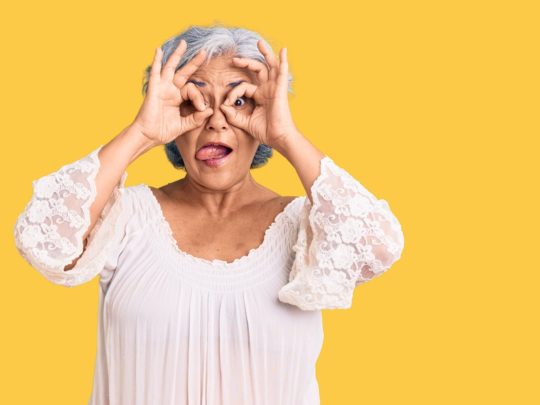 En kvinna som gör kikare med fingrarna.